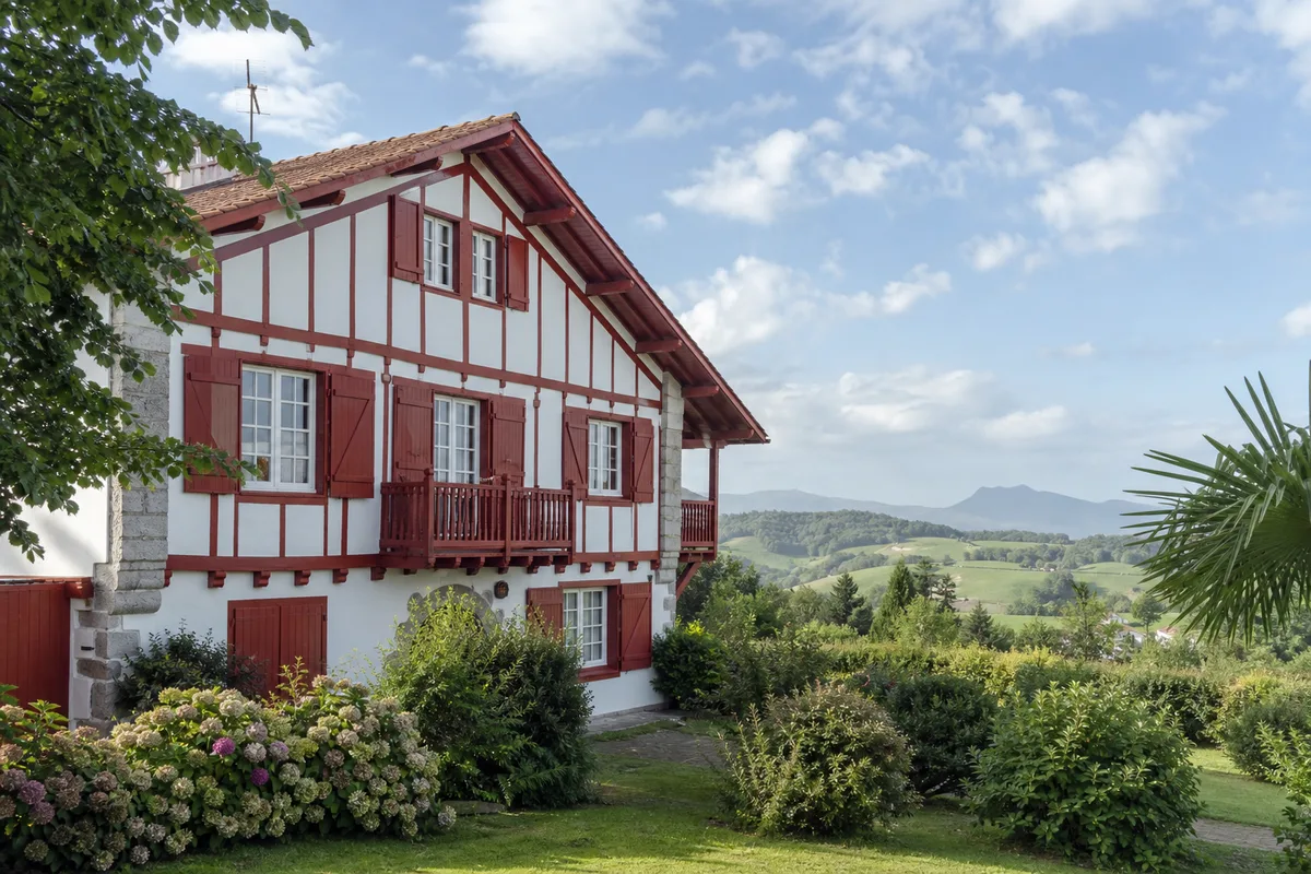 Villa labourdine aux colombages rouge basque entourée de verdure près d&rsquo;Arcangues